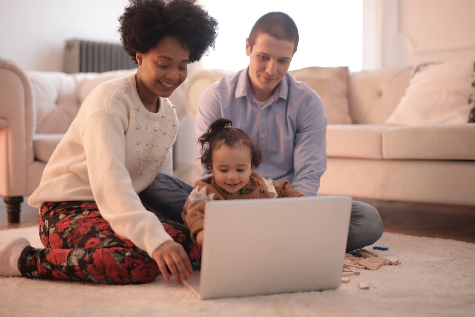 Photo of a family sitting on the floor using a laptop together