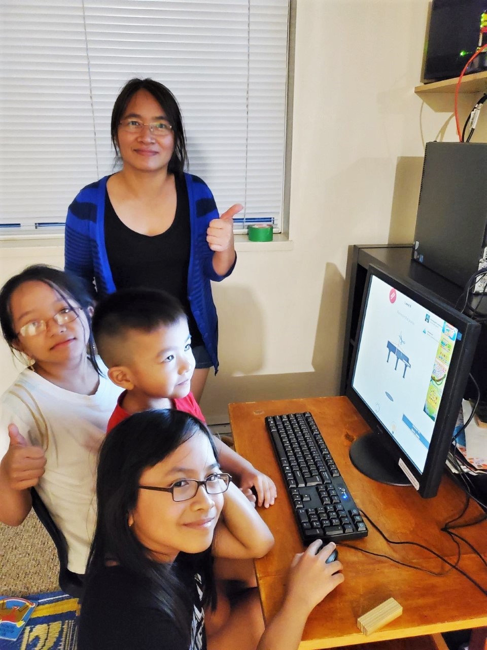 Zong May and her three children using their donated computer